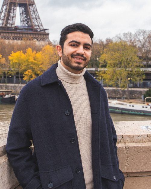 Himanshoo in a navy coat by the Seine, with the Eiffel Tower behind him